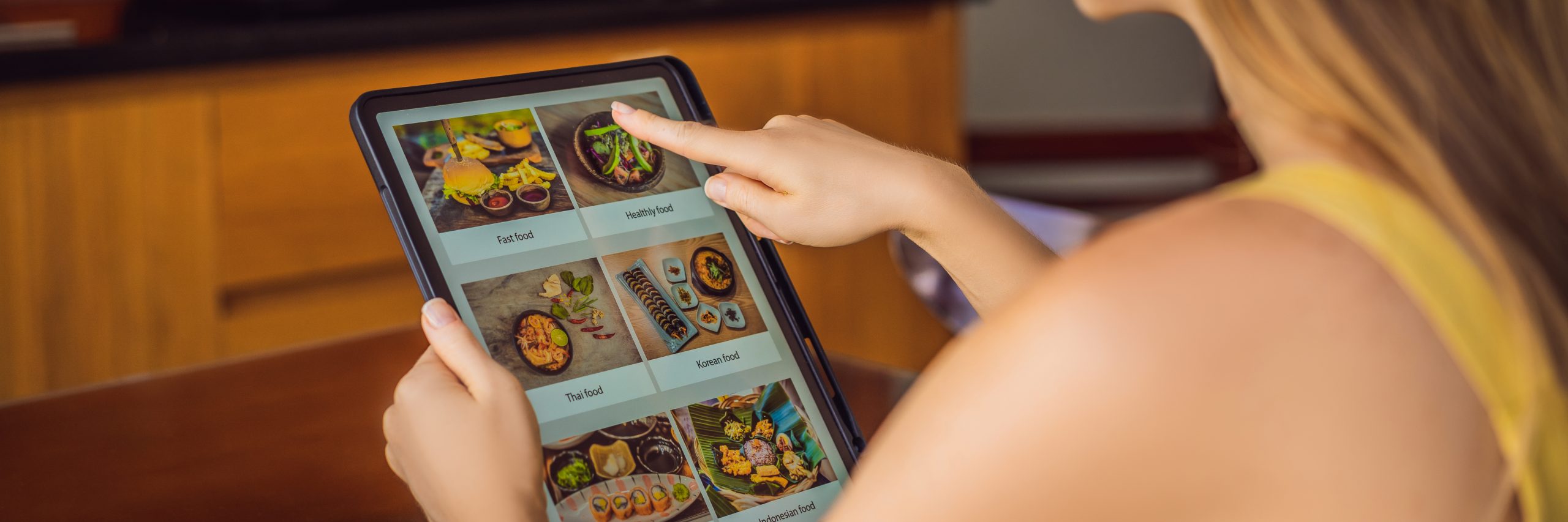 Young woman orders food for lunch online using Tablet BANNER, LONG FORMAT